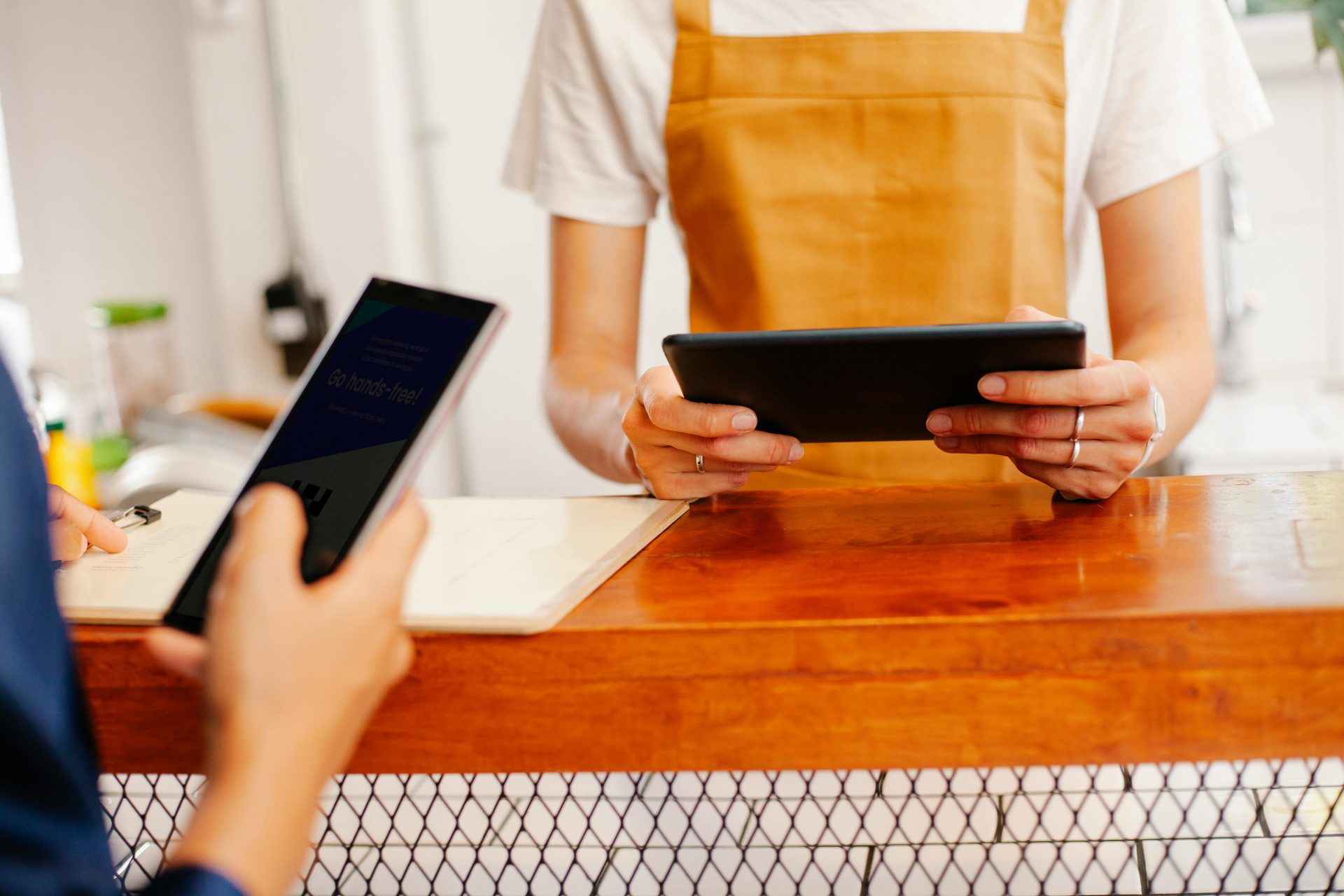 Faceless cafeteria partners using smartphone and tablet at counter